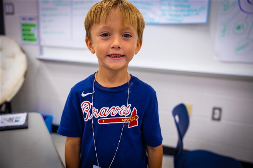 A blond boy smiles during a science experiment